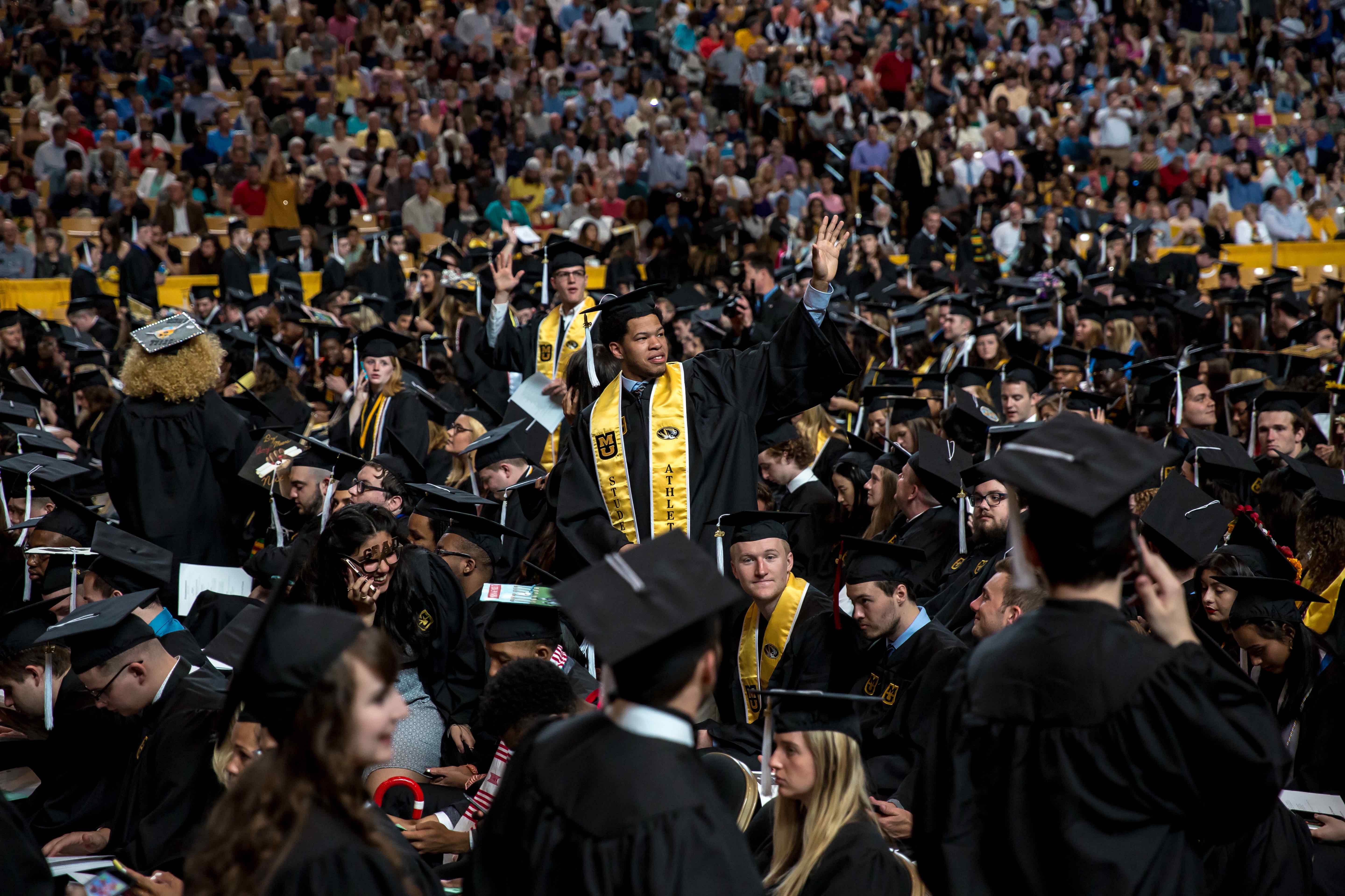 Photo depicting a large A&S graduation crowd with one graduate standing.