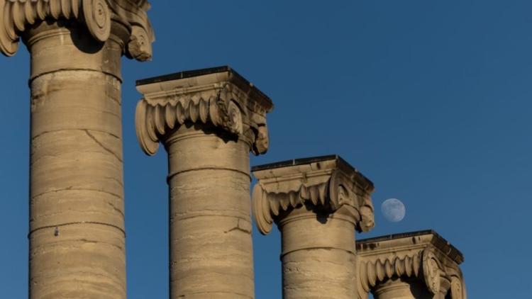 The top of the columns, the sky is blue, and you can see the moon above the column