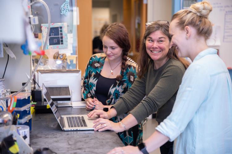 A photo of three people looking at research